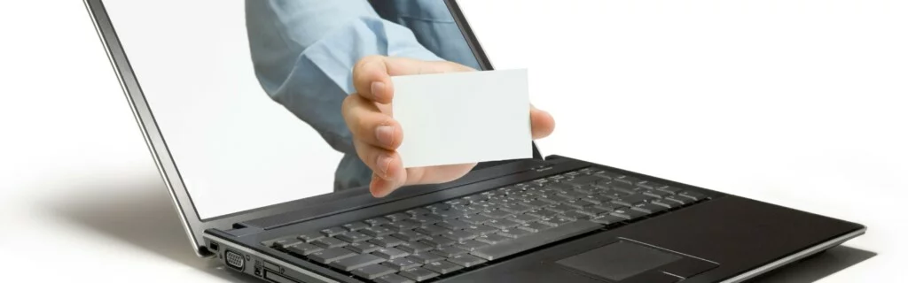 Eine Hand greift aus einem Laptop-Bildschirm heraus und hält eine Visitenkarte hin.